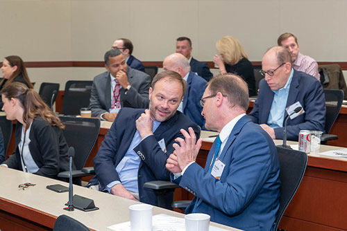 Two seated attendees smile and enjoy face-to-face networking during a break between sessions at the 2022 Chicago Payments Symposium.