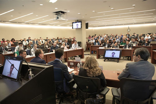 A view of the 2024 Chicago Payments Symposium audience from behind five panelists seated at the front of the auditorium.