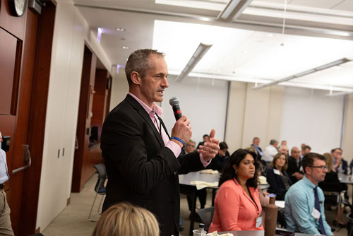 An attendee holding a microphone asks a question during a keynote session at the 2024 Chicago Payments Symposium.