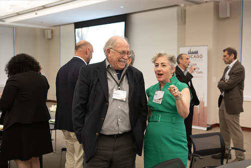 A panelist at the 2024 Chicago Payments Symposium chats with an attendee while other attendees network in the background.