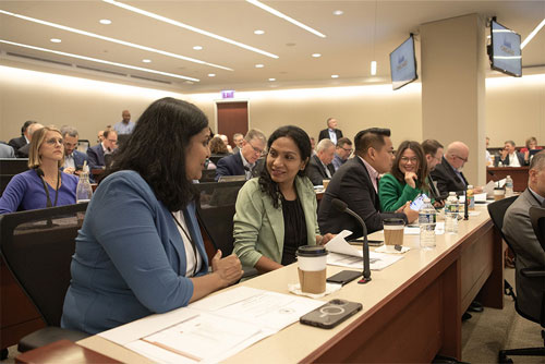 Two seated attendees smile and enjoy face-to-face networking during a break between sessions at the 2024 Chicago Payments Symposium.
